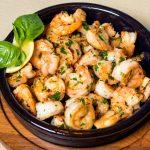 cooked frozen shrimp in a bowl garnished with a lemon wedge and herbs