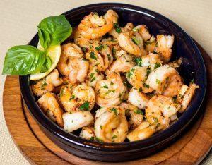 cooked frozen shrimp in a bowl garnished with a lemon wedge and herbs