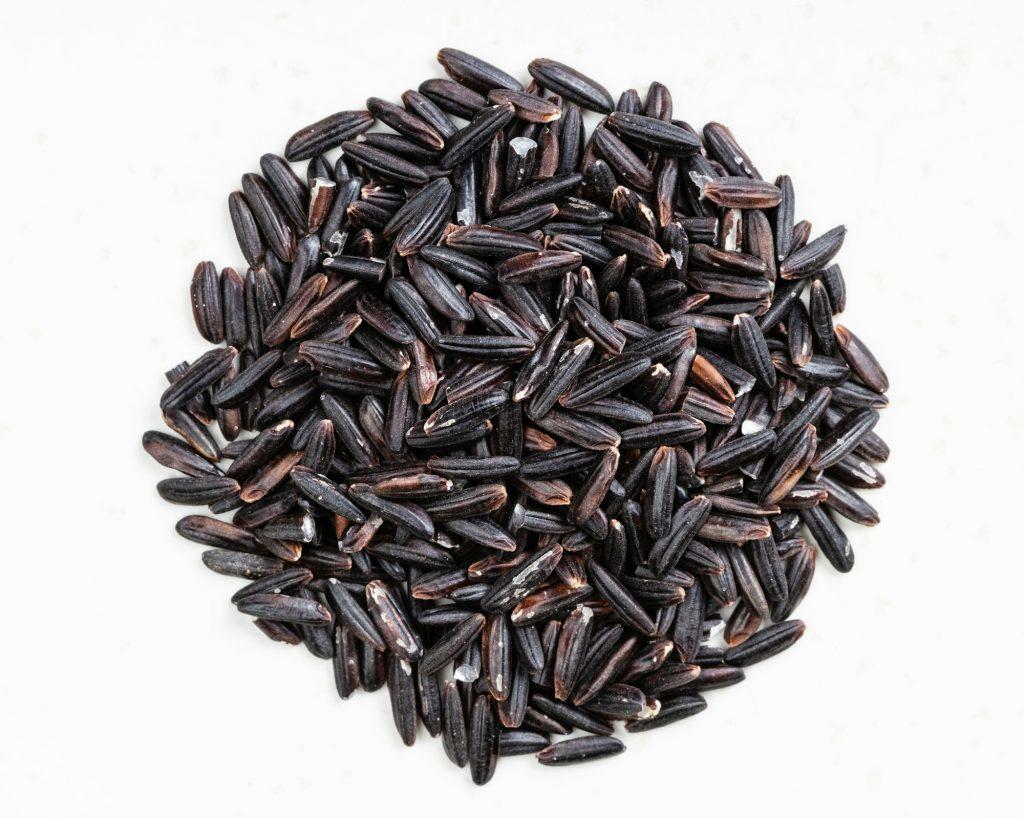 pile of raw black rice close up on gray