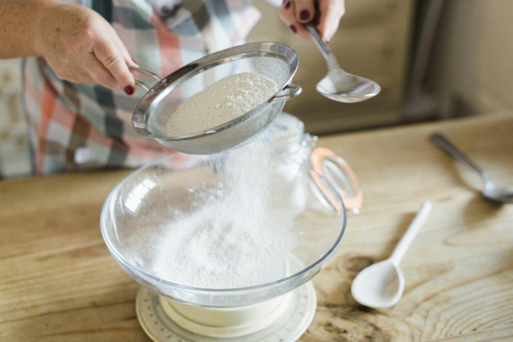 A woman measuring and sifting white flour. Home baking.