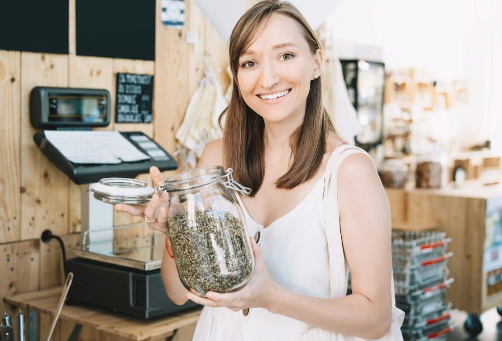 Girl holds glass jar with hemp seeds in zero waste shop