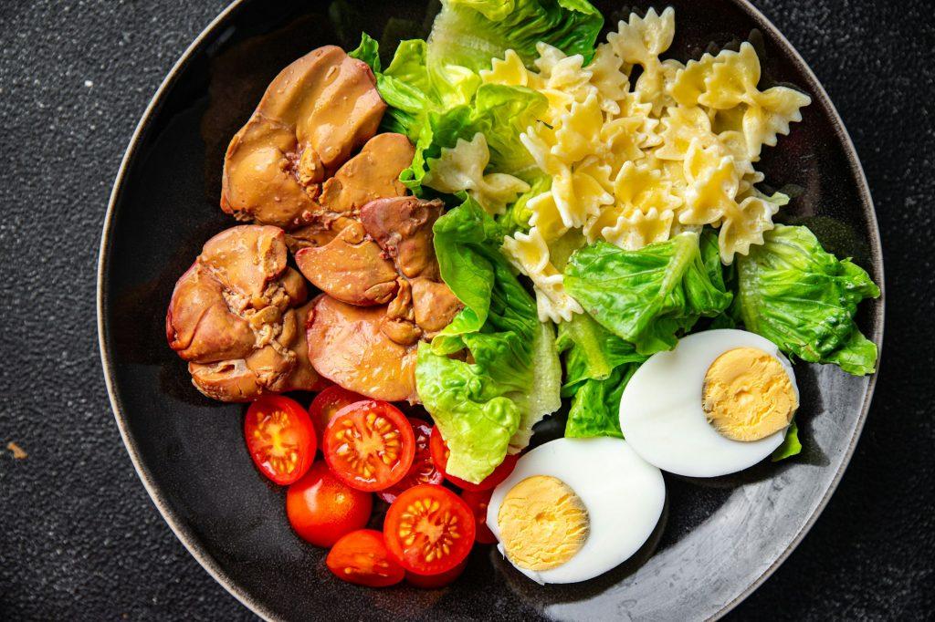 salad chicken liver, pasta, tomato, green leaf lettuce, boiled egg, farfalle snack meal