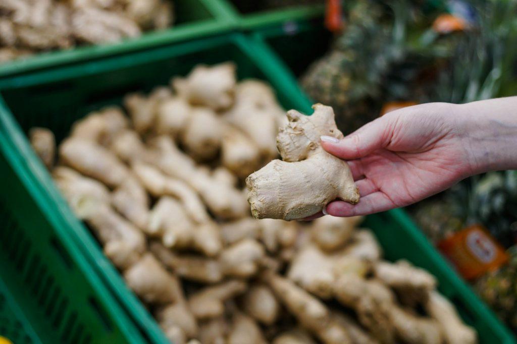 Woman choosing ginger in the supermarket. Close up of hand holding fresh ginger at store.